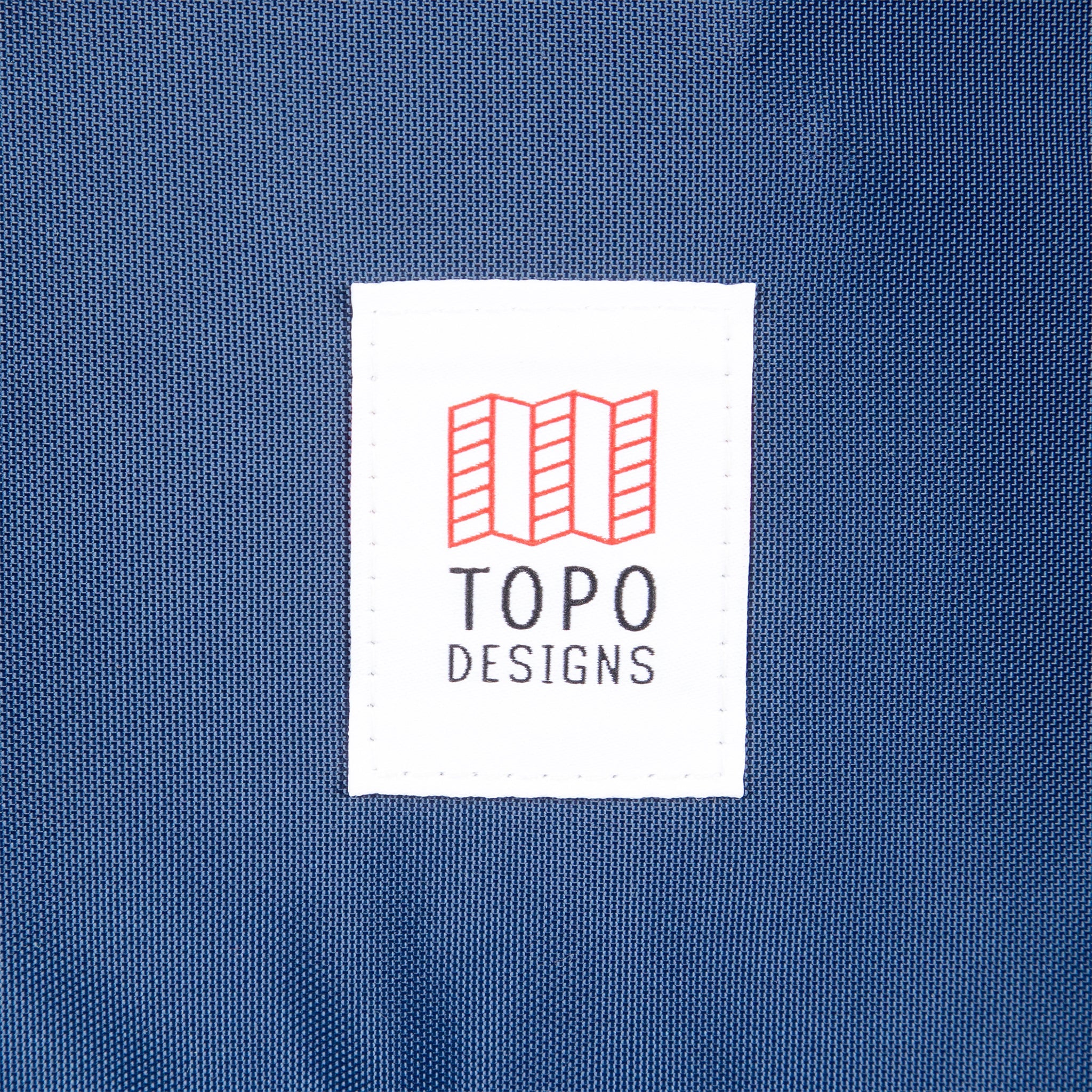 General shot of Topo Designs logo patch on Global Travel Bag 40L Durable Carry On Convertible Laptop Travel Backpack in Navy blue.