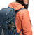 Model wearing Topo Designs Women's Global Puffer recycled insulated packable Hoodie jacket in "coral" pink