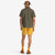 Back of model wearing Topo Designs Men's Global Shirt Short Sleeve 30+ UPF rated travel shirt in Olive green.