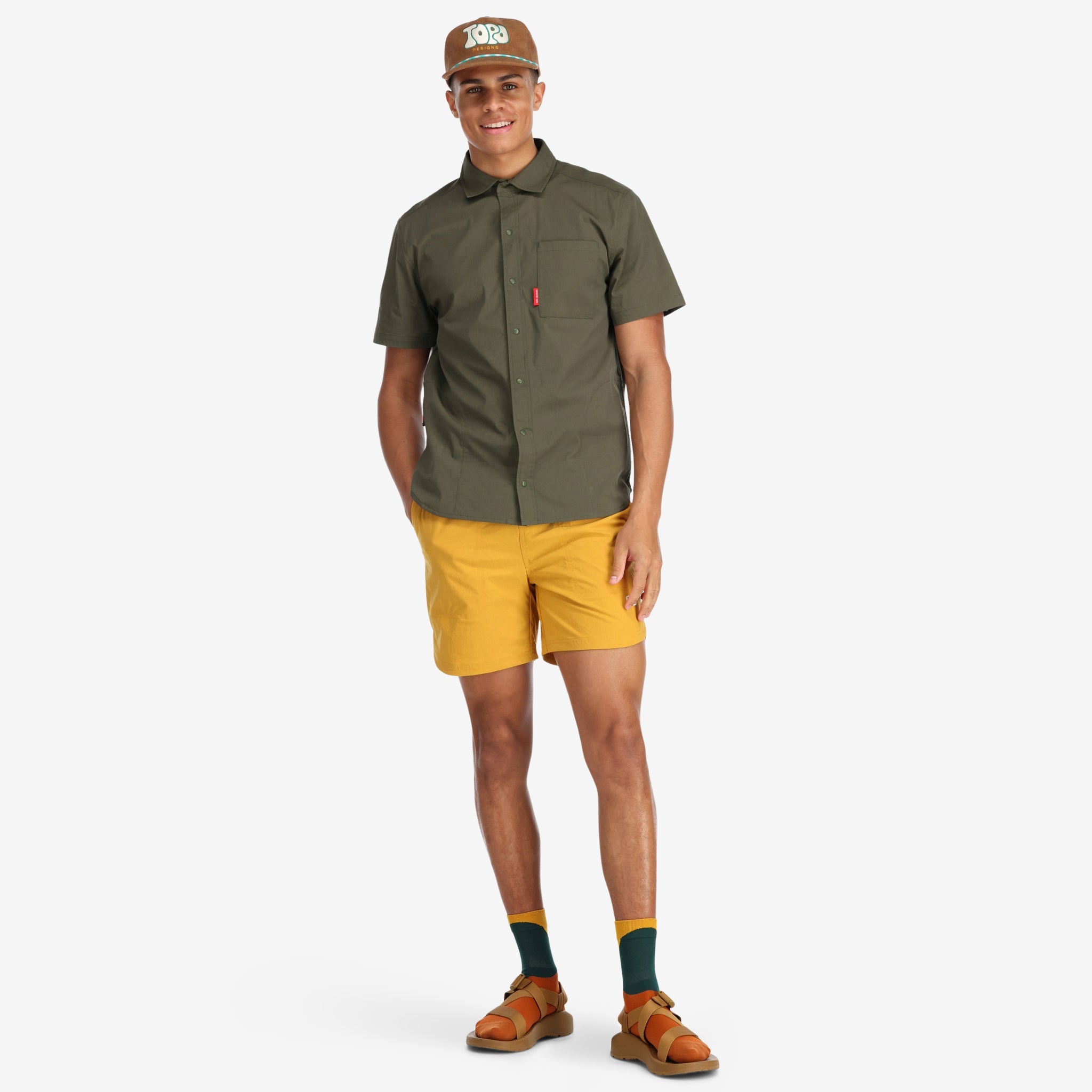 Model wearing Topo Designs Men's Global Shirt Short Sleeve 30+ UPF rated travel shirt in Olive green.