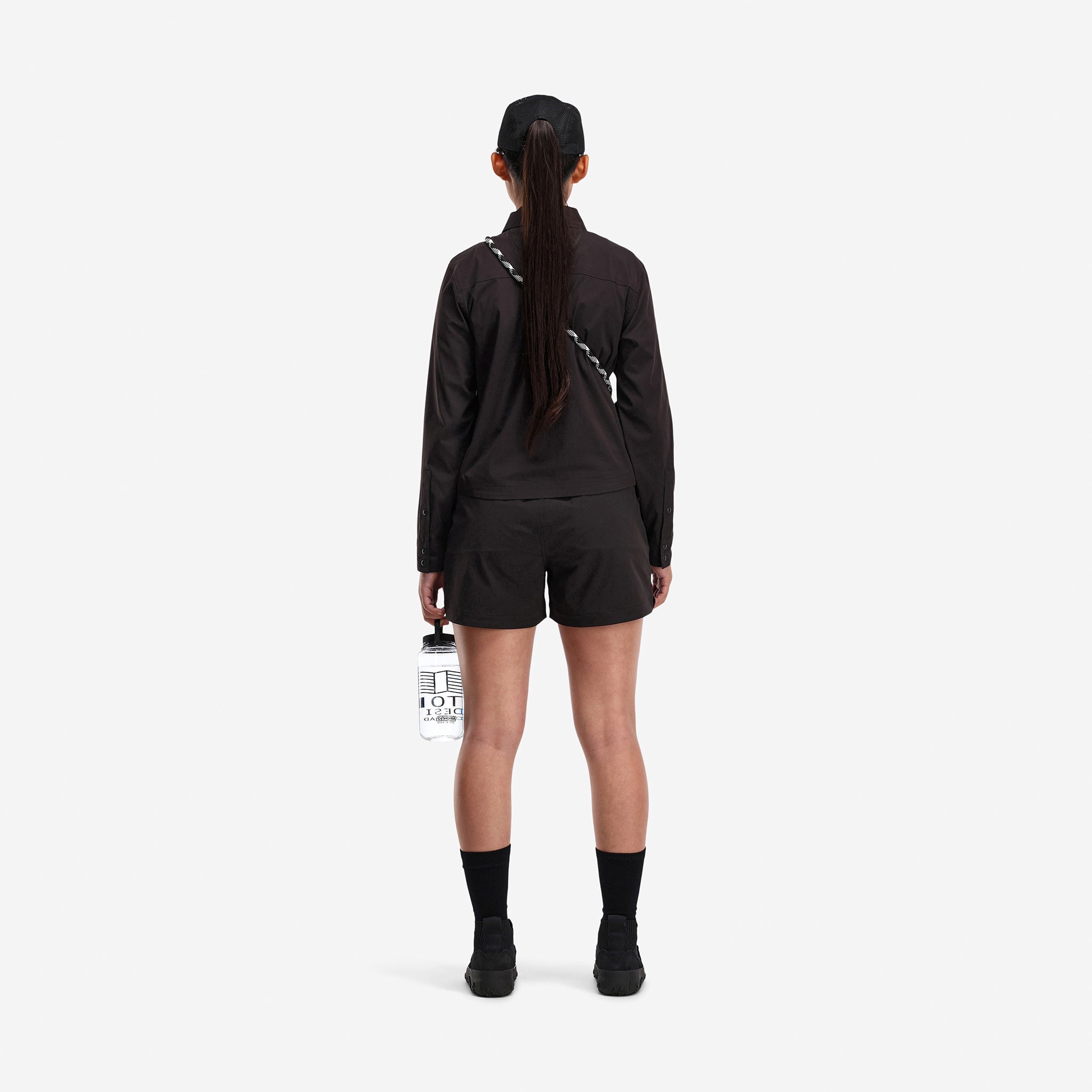 Back model shot of Topo Designs Women's Global long sleeve lightweight snap travel shirt in "black"