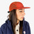 Model wearing Topo Designs Global mesh back Hat in "Clay" orange