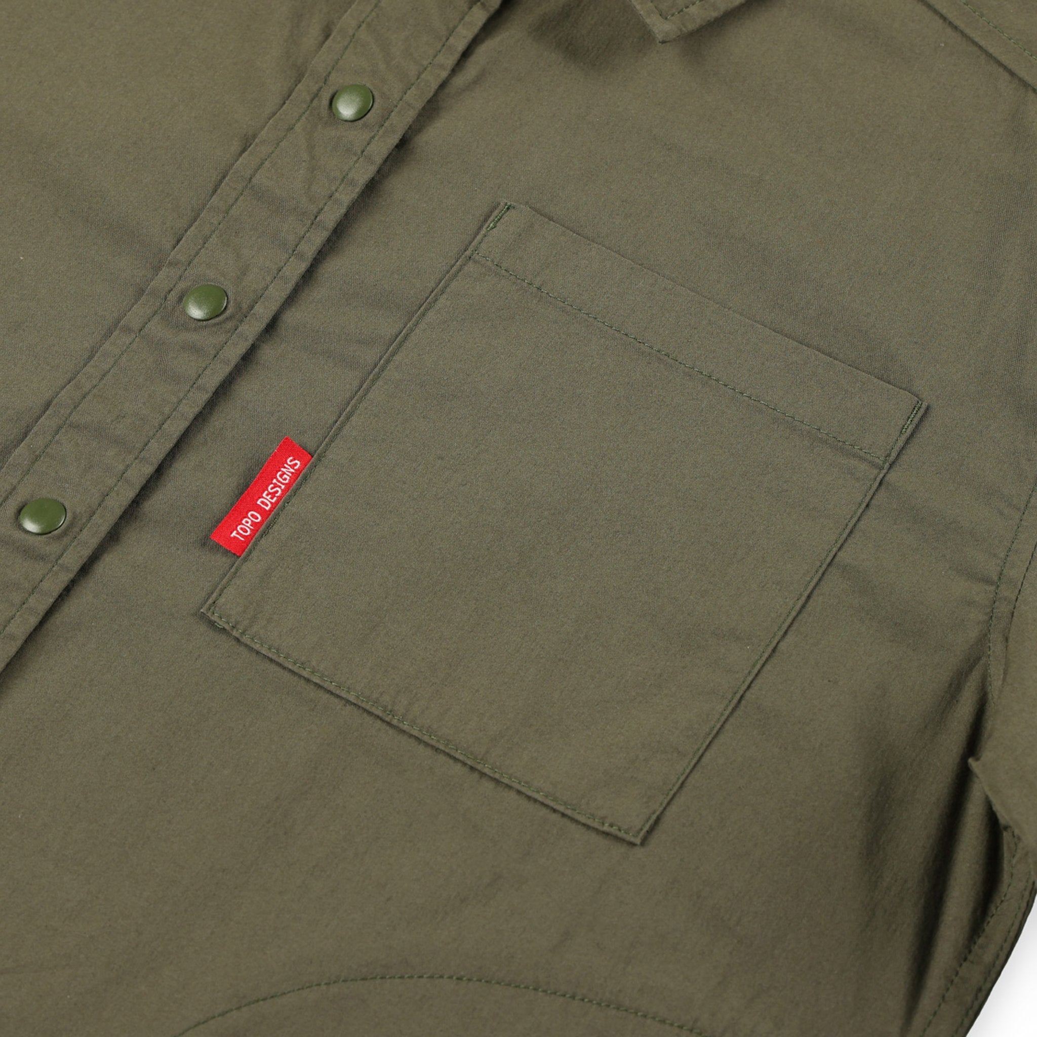 General shot of Topo Designs Women's Global long sleeve lightweight snap travel shirt in olive green showing front chest pocket detail.