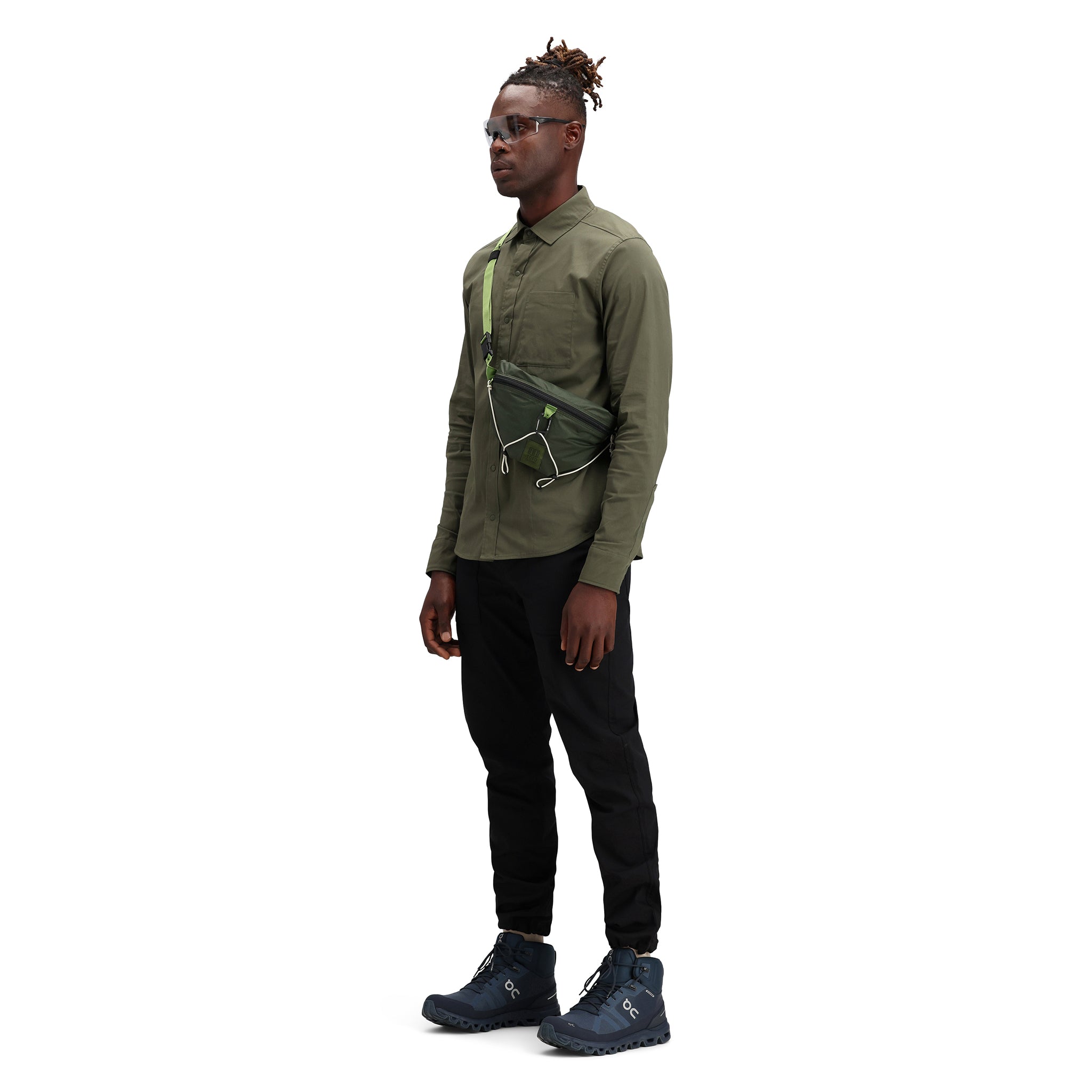 Model wearing Topo Designs Men's Global Shirt long sleeve lightweight travel snap shirt in "olive" green. Show on "Pond Blue".