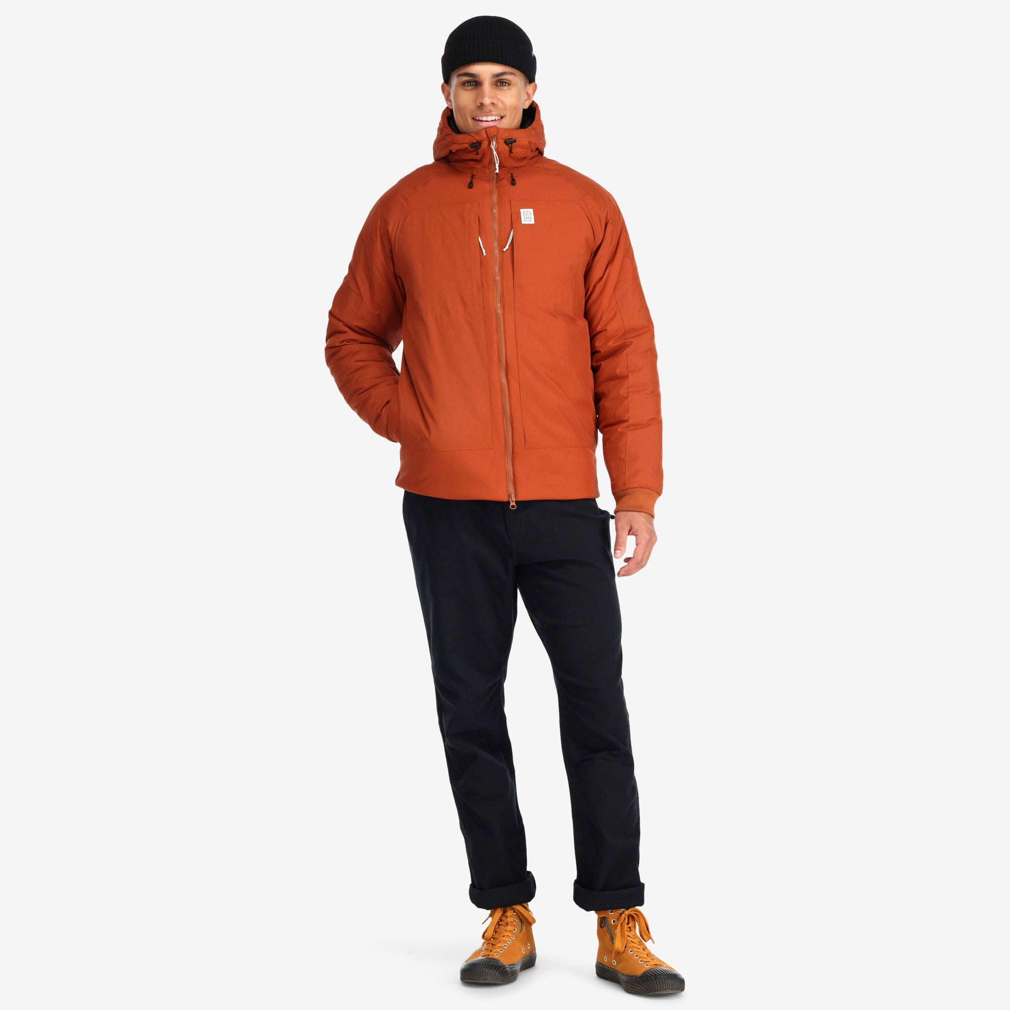 Front model shot of Topo Designs Mountain Puffer Primaloft insulated Hoodie jacket in "Brick" orange