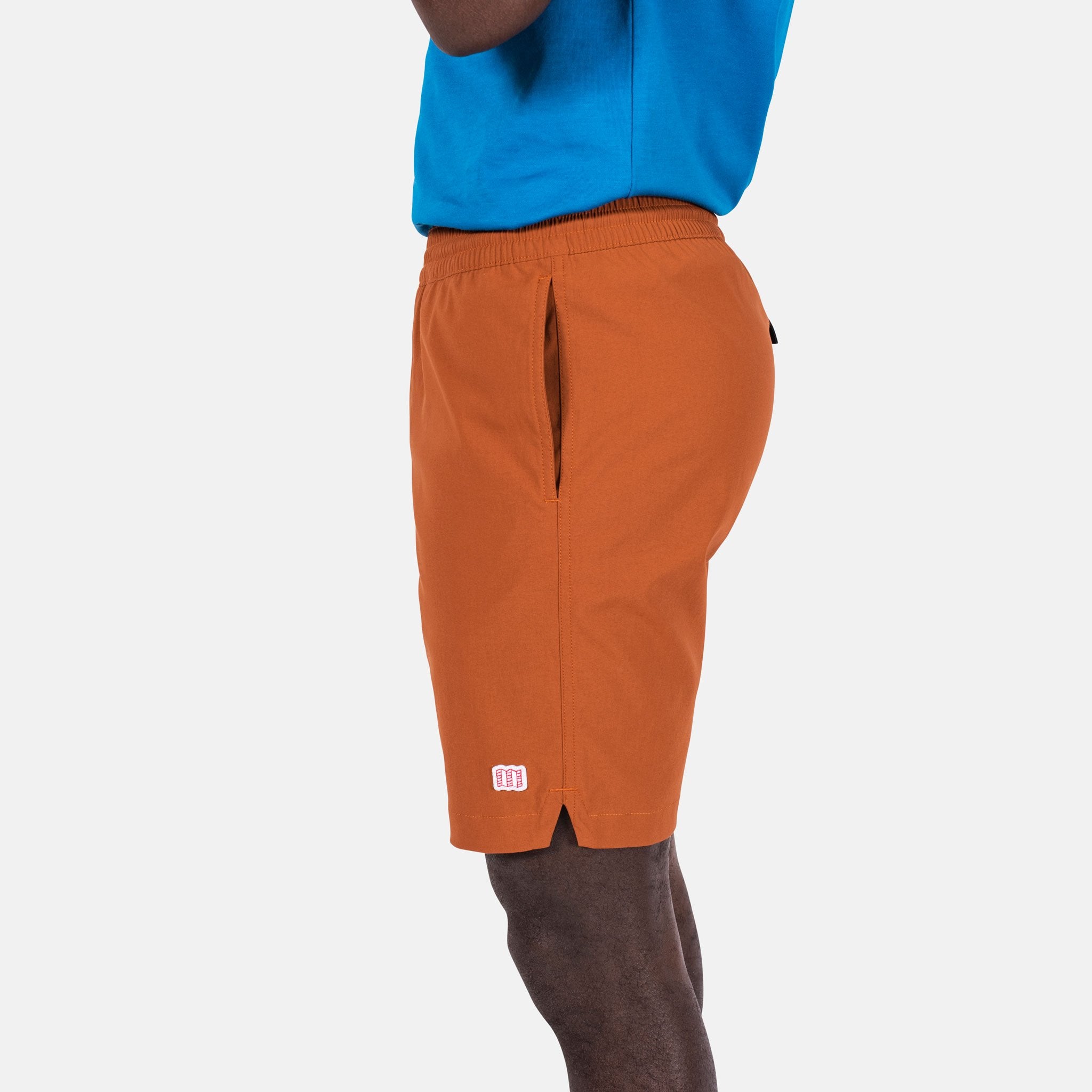 Close-up side model shot of Topo Designs Men's Global Shorts in Brick orange.