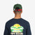 Back of model wearing Topo Designs Corduroy Trucker Hat with embroidered Sunset graphic in olive green.
