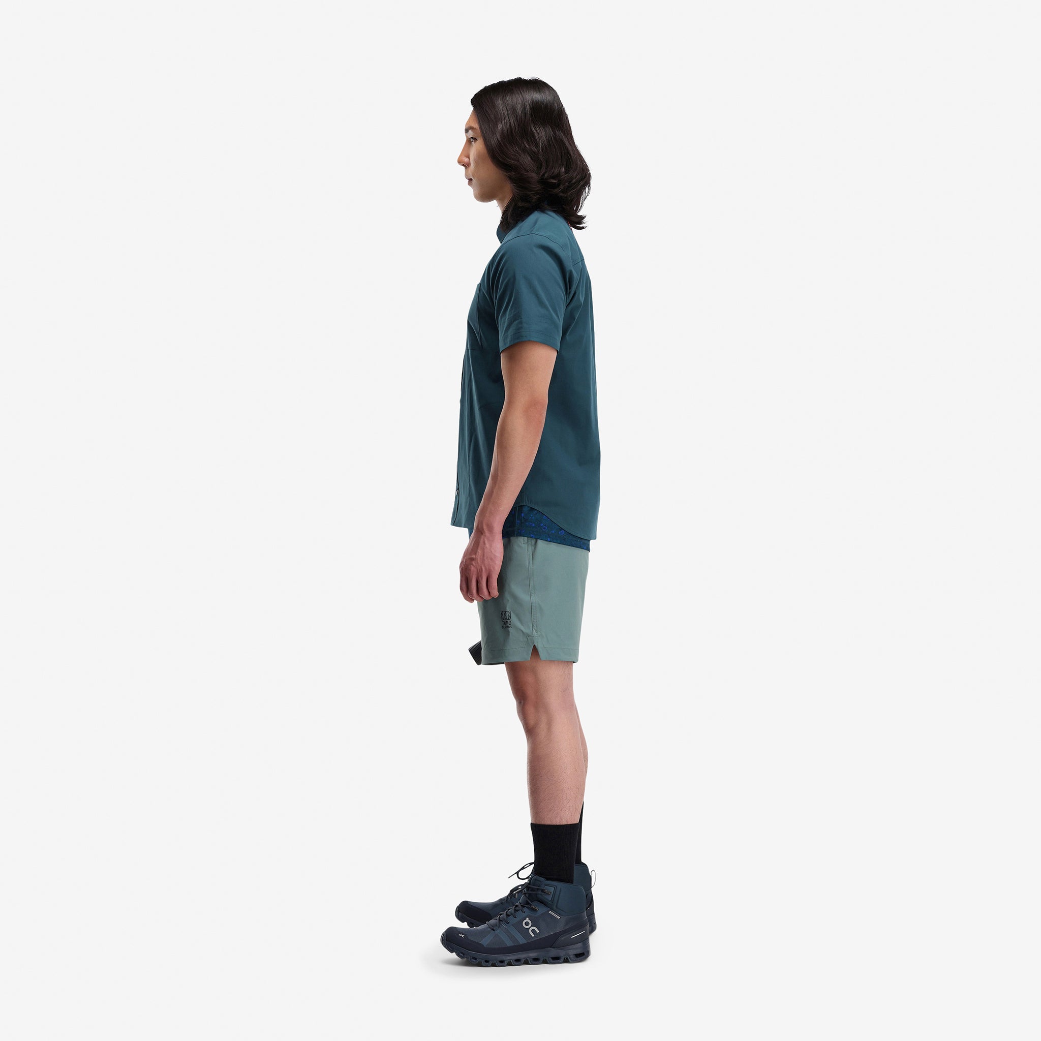 Side model shot of Topo Designs Men's Global lightweight quick dry travel Shorts in "Slate" blue gray. Show on "pond blue" and "brick".