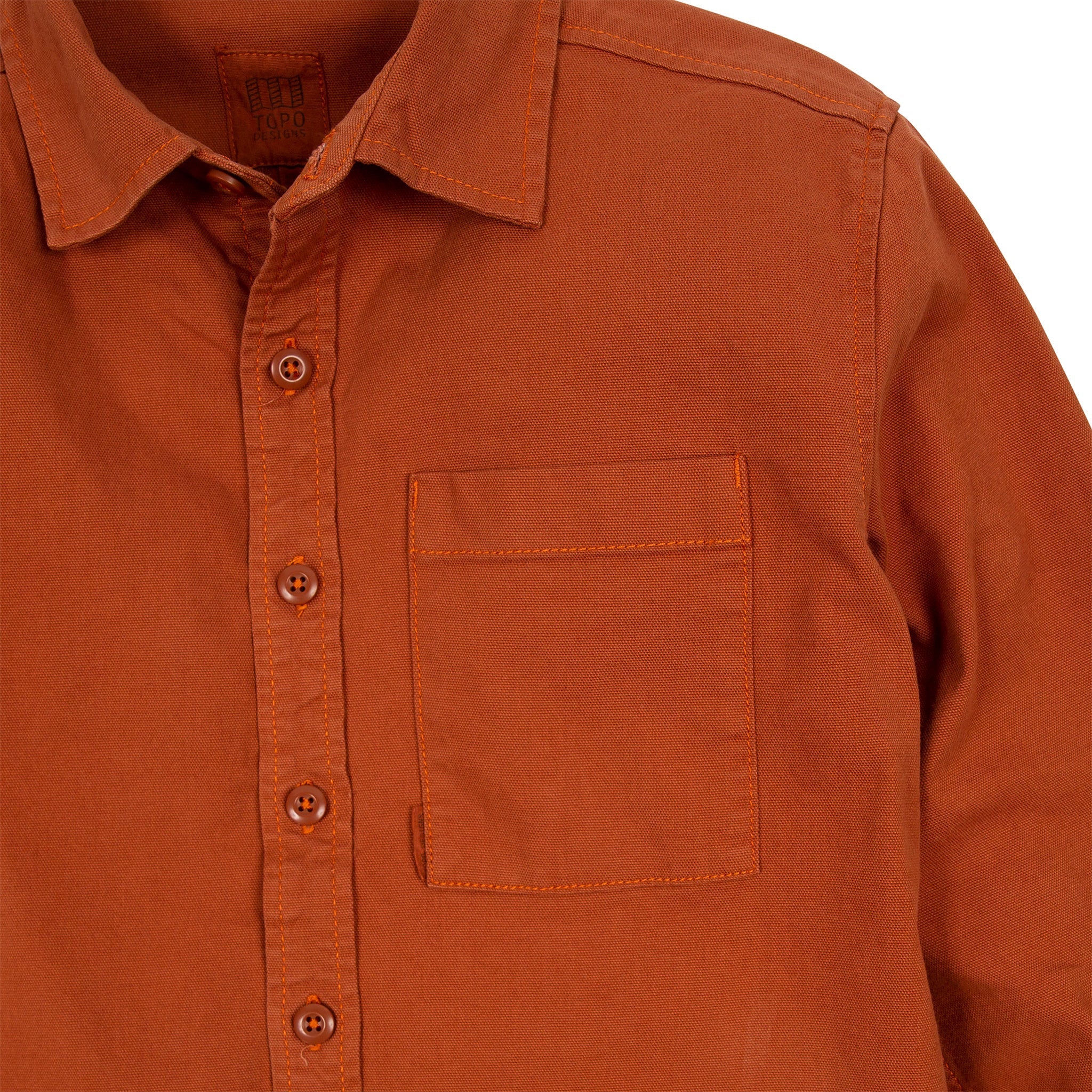 Detailaufnahme des Topo Designs Herren Dirt Shirt in Brick Orange mit Knöpfen und Brusttasche.