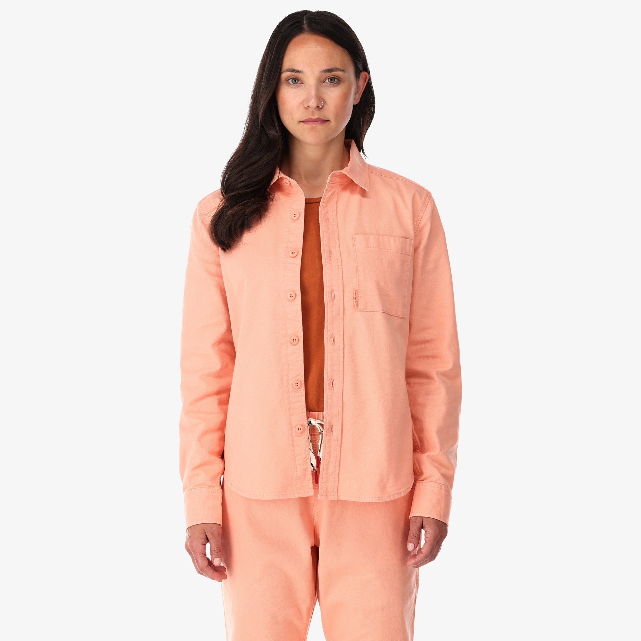 Topo Designs Damen Dirt Shirt langärmeliges Button-up aus Stretch-Baumwolle in "Pfirsich"-rosa auf der Modellfront.