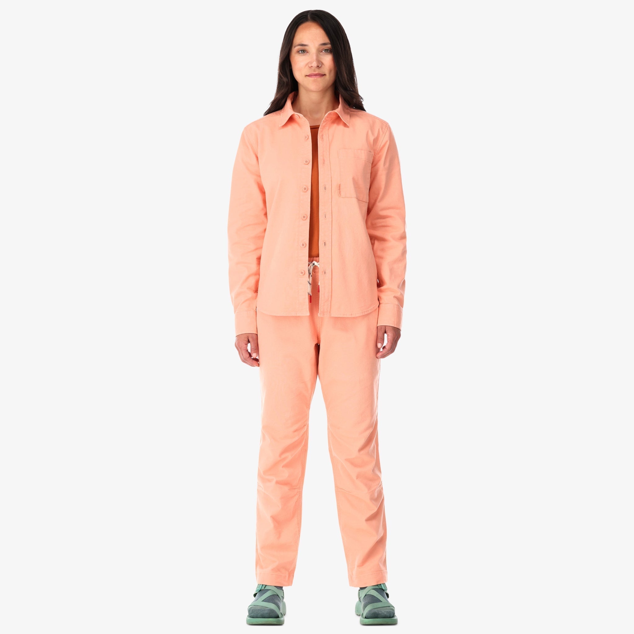 Topo Designs Damen Dirt Shirt langärmeliges Button-up aus Stretch-Baumwolle in "Pfirsich"-rosa auf der Modellfront.