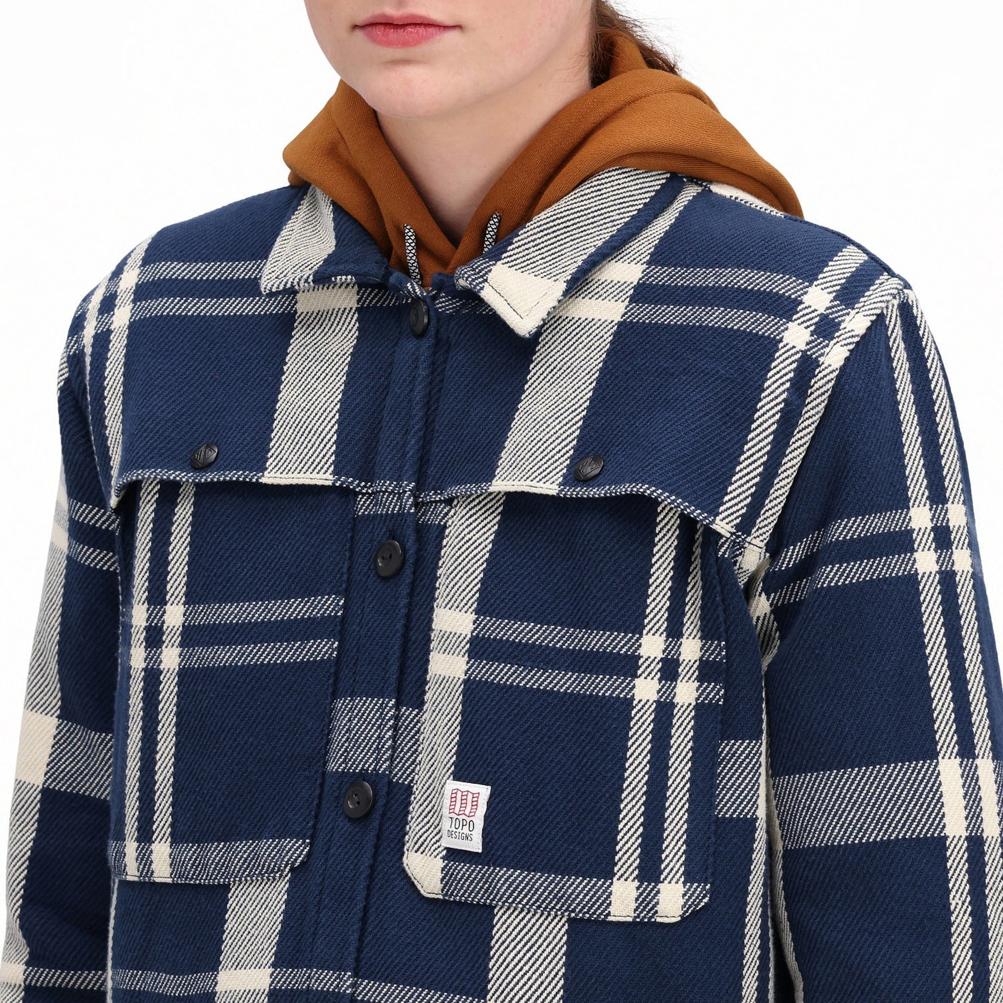 Detailaufnahme des Modells der Topo Designs Damen Mountain Shirt Jacket in "navy / white plaid" mit Brusttaschen und Knöpfen.