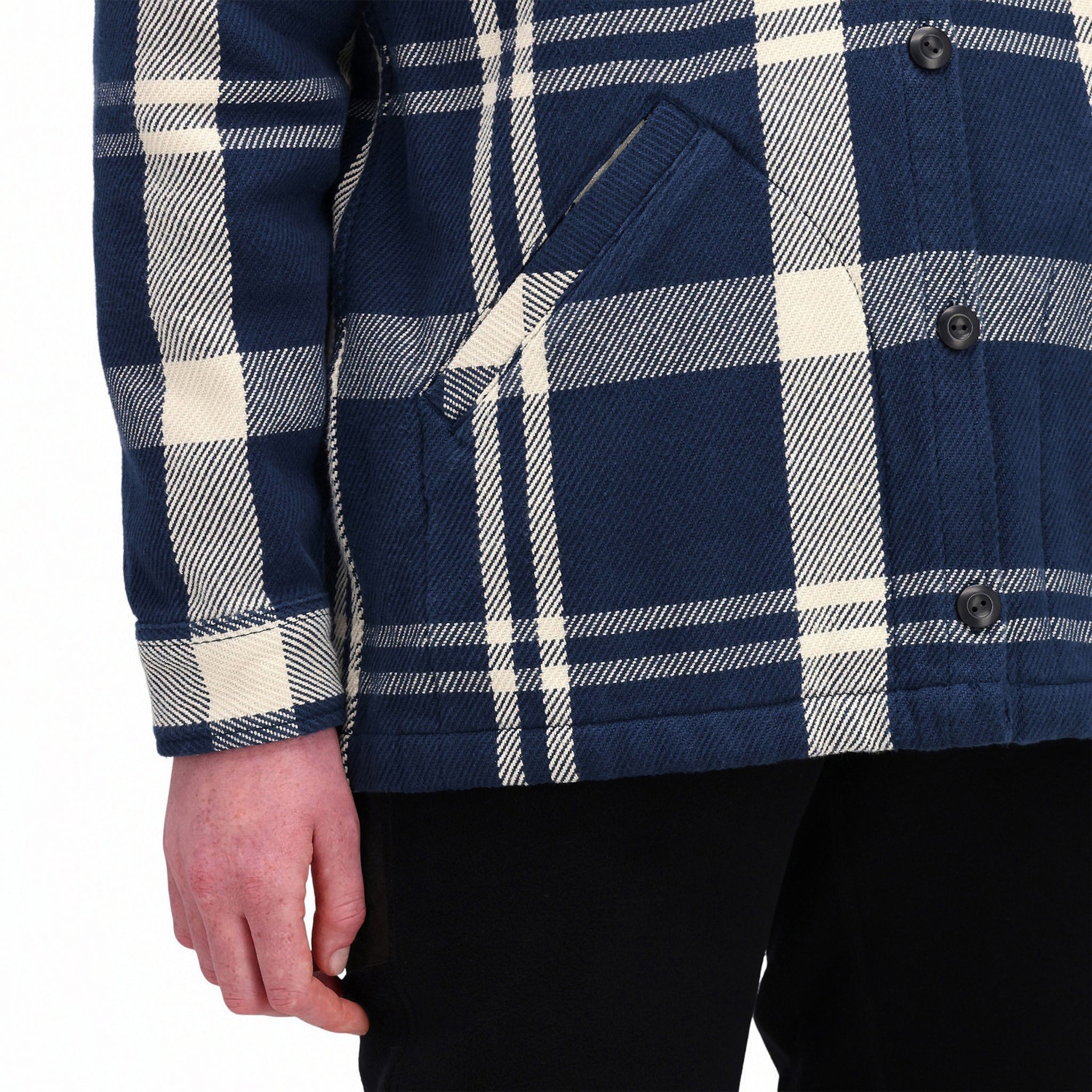 Detailaufnahme des Modells der Topo Designs Damen Mountain Shirt Jacket in "navy / white plaid", die die Eingrifftaschen und die Manschette zeigt.