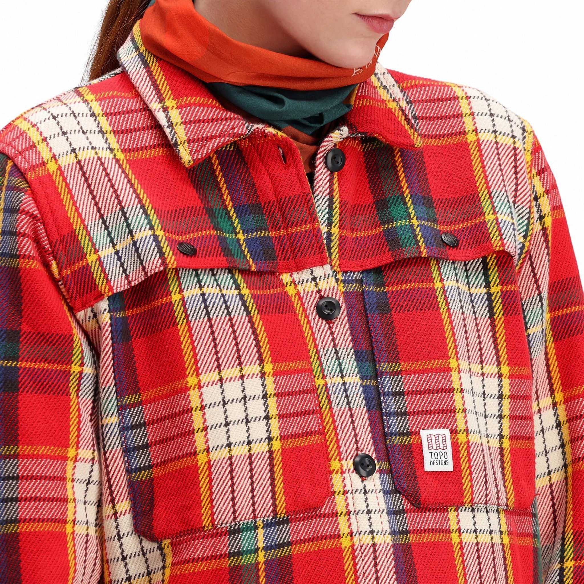 Detailaufnahme des Modells der Topo Designs Damen Mountain Shirt Jacket in "rot/gelb kariert" mit Brusttaschen und Knöpfen. Zeige auf "braun / natur kariert"