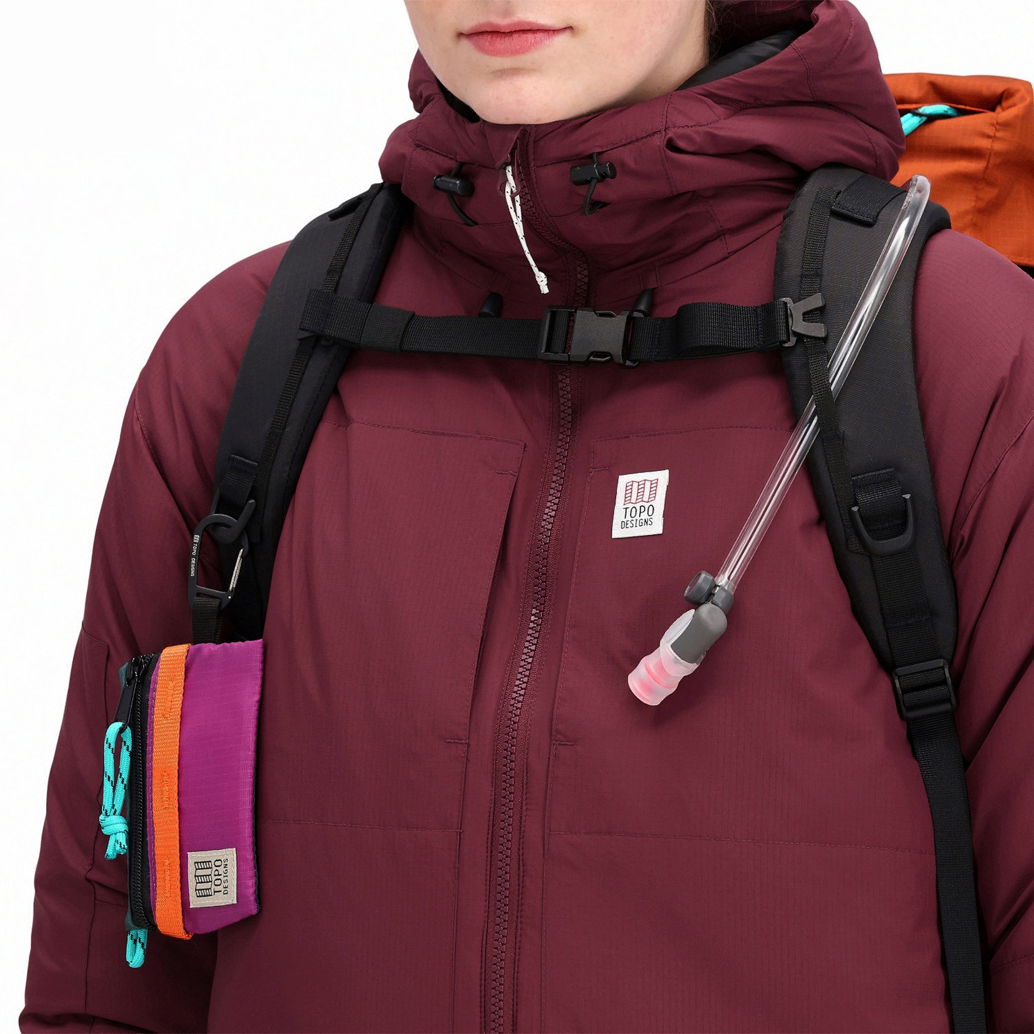 Allgemeine Frontmodellaufnahme der Topo Designs Damen Puffer Primaloft isolierten Hoodie Jacke in "burgundy" rot mit Brustreißverschlusstaschen und Logo.