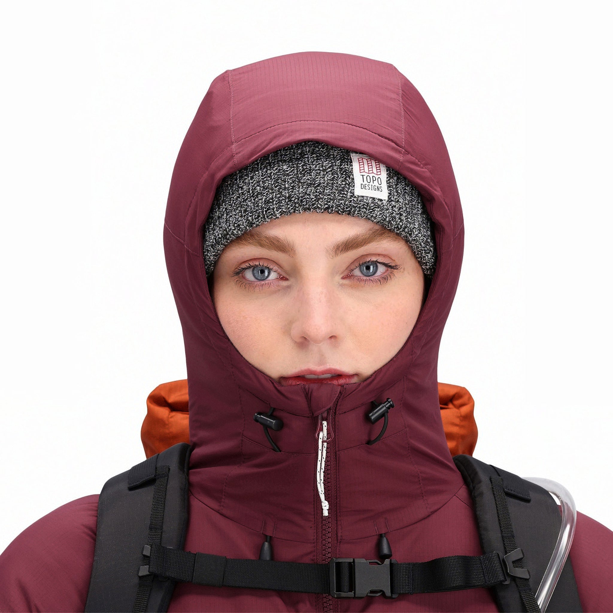 Allgemeine Frontmodellaufnahme der Topo Designs Damen Puffer Primaloft isolierten Hoodie Jacke in "burgundy" rot mit Kapuzendetails.