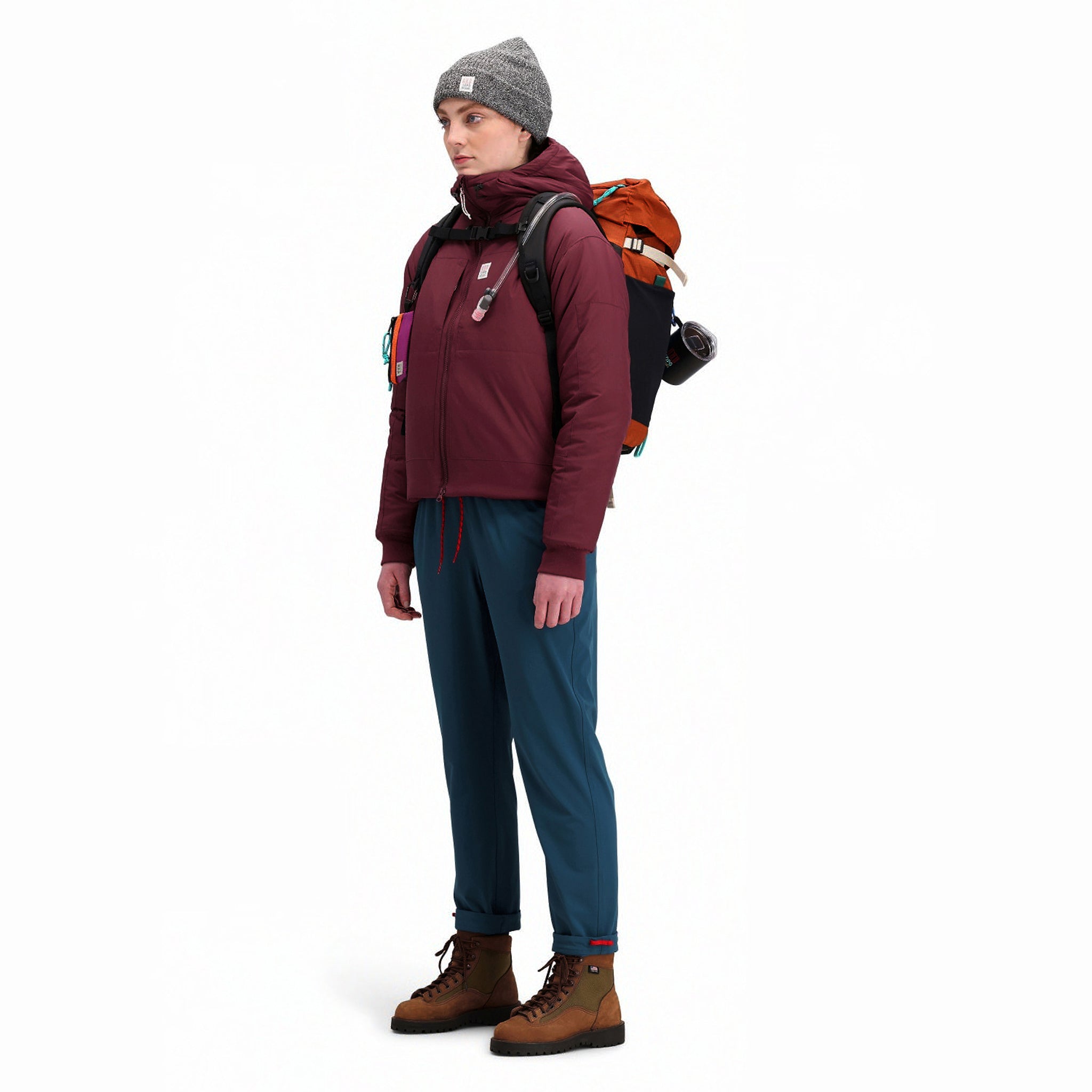 Seitliche Modellaufnahme der Topo Designs Damen Puffer Primaloft insulated Hoodie Jacke in "burgundy" rot.