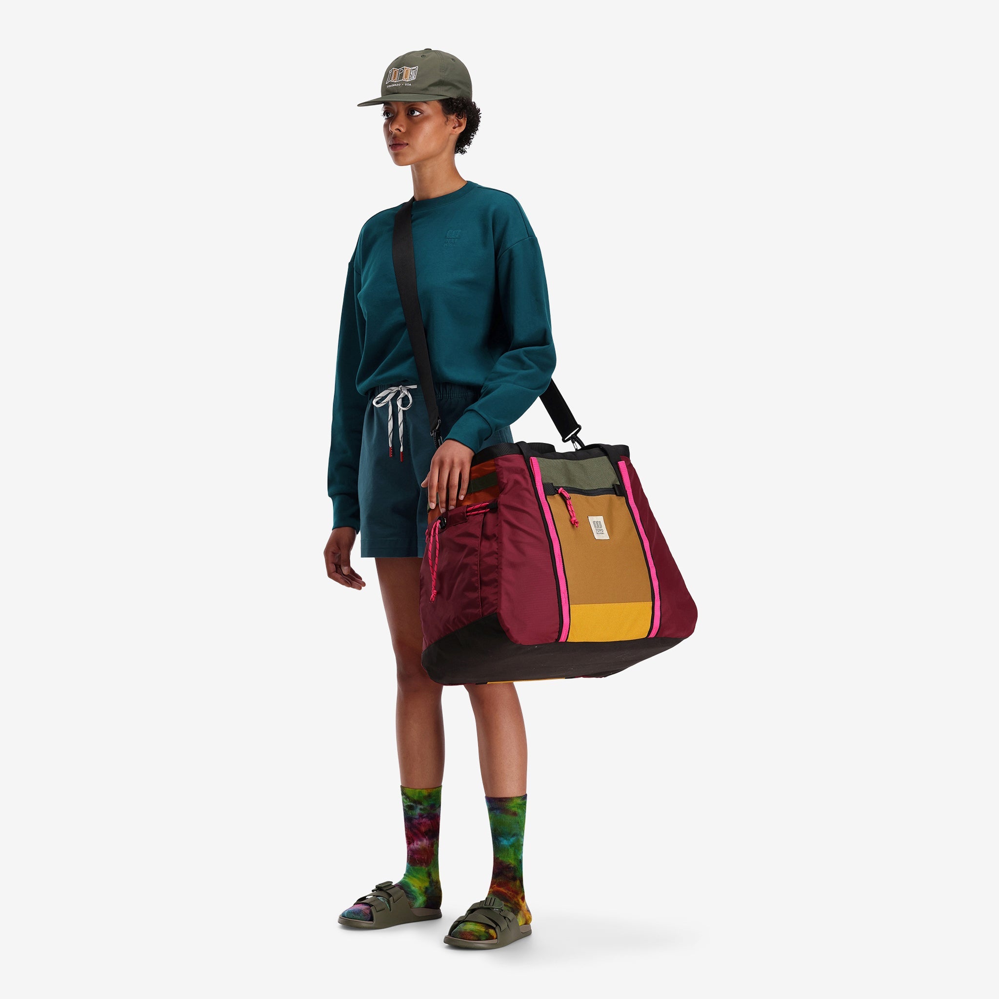 Linke Seite Modell Schuss von Topo Designs Mountain Gear Bag Tote Hauler in leichten recycelten in "Burgundy / Dark Khaki " Nylon zeigt Schultergurt tragen.