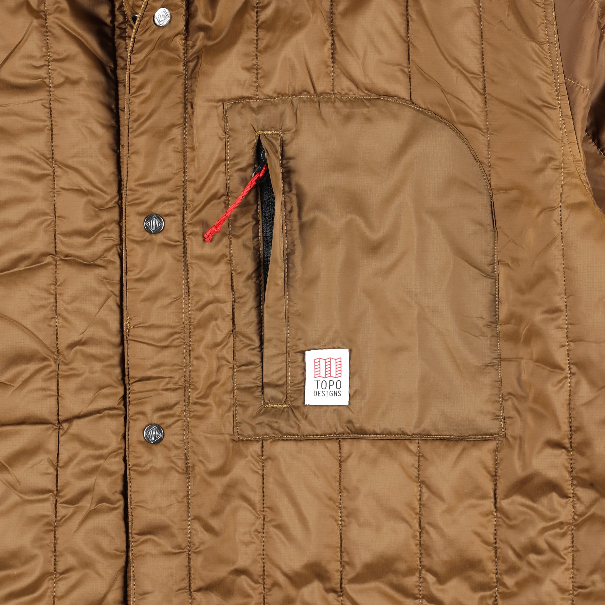 Detailaufnahme der Brusttasche mit Reißverschluss auf der Vorderseite des Modells Topo Designs Herren Insulated Reversible Shirt Jacket in "dark khaki" braun