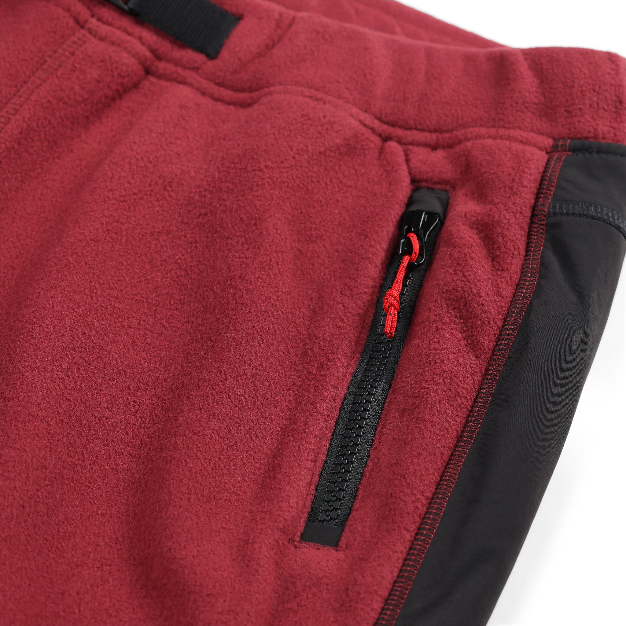 Allgemeine Detailaufnahme der Reißverschlusstaschen der Topo Designs Damen Fleece Hose in "Burgundy / Black"