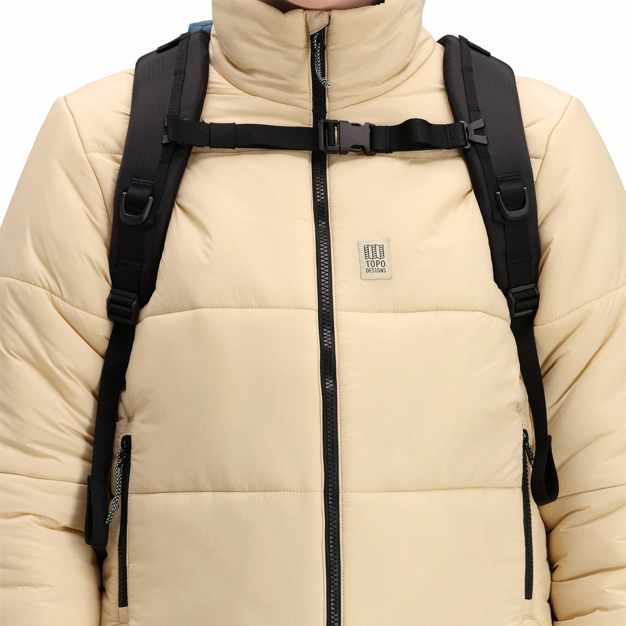 Vordere Modellaufnahme der Topo Designs Damen Puffer recycelten isolierten Jacke in "Sand" weiß mit Reißverschluss, Brustlogo und Reißverschlusshandtaschen.