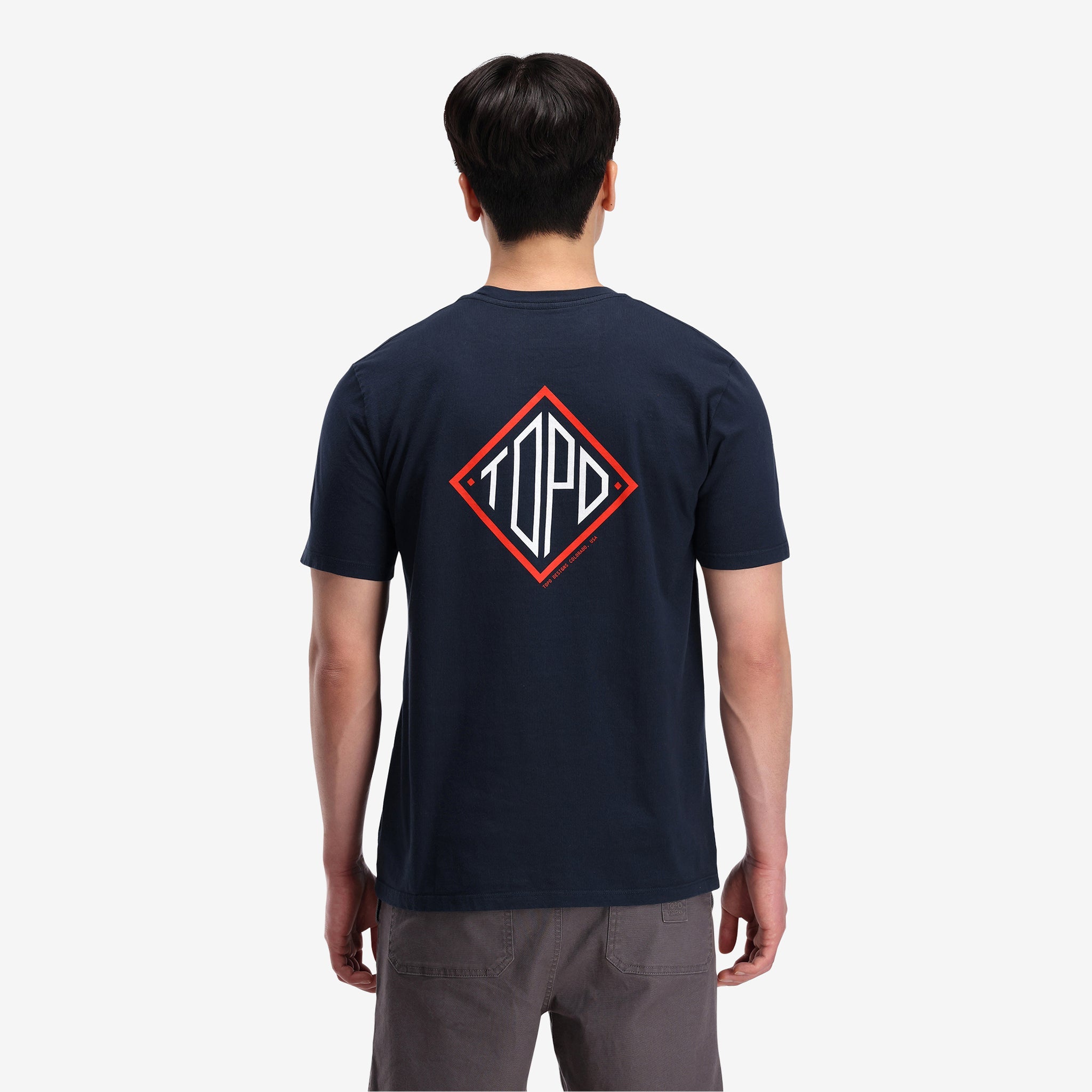 Rückenansicht des Topo Designs Herren Small Diamond Tee aus 100% Bio-Baumwolle, kurzärmeliges Logo-T-Shirt in "navy"-Blau, auf dem Modell.