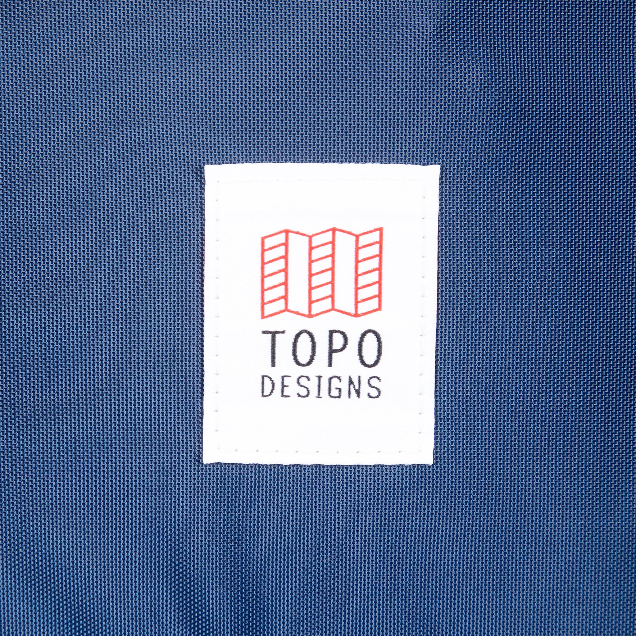 Vue générale du logo Topo Designs sur le Global Travel Bag 40L Durable Carry On Convertible Laptop Travel Backpack en bleu marine.