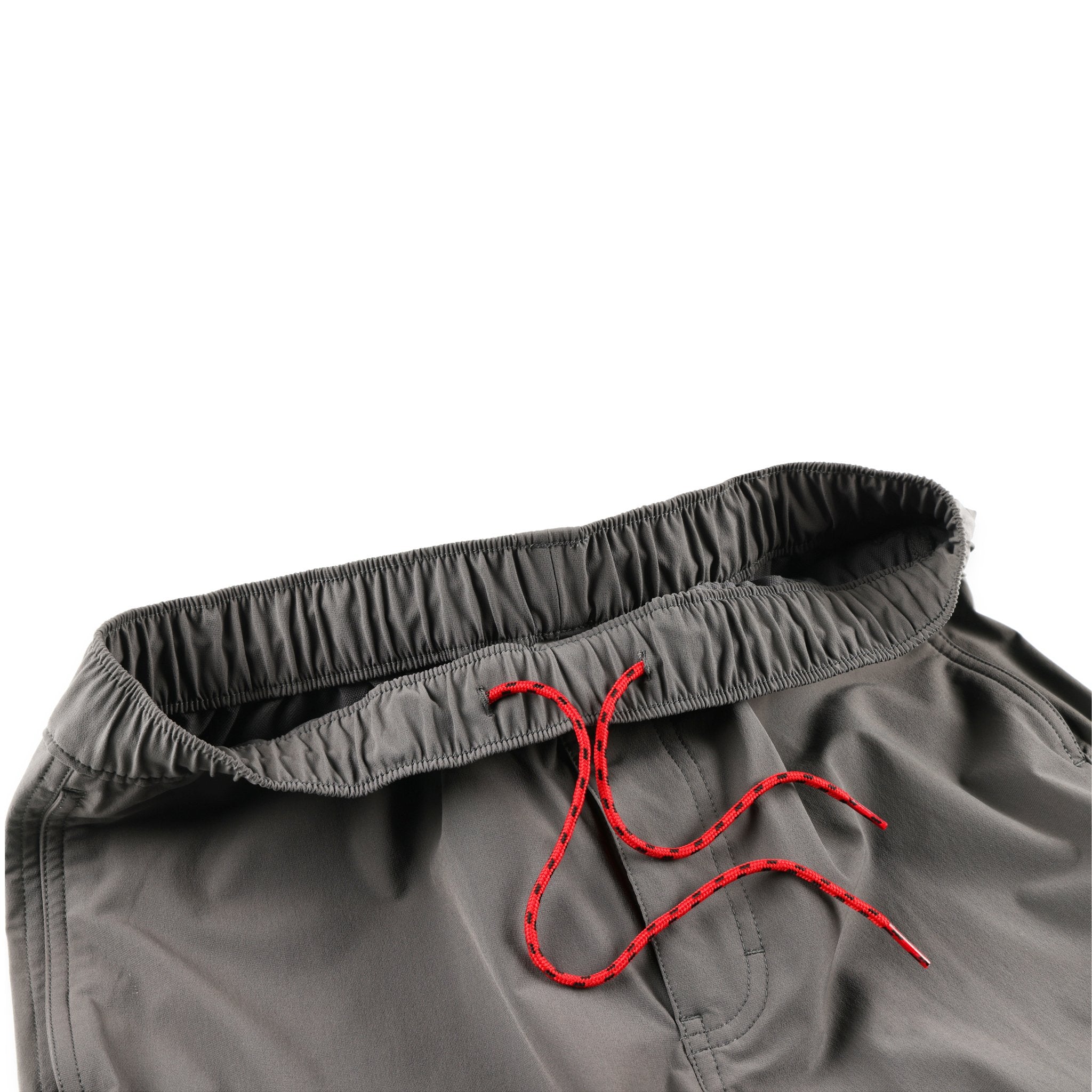 Vue générale du Pantalon escalade et de randonnée Topo Designs Hommes Boulder lightweight en gris anthracite montrant le cordon de serrage rouge dans la ceinture élastique.