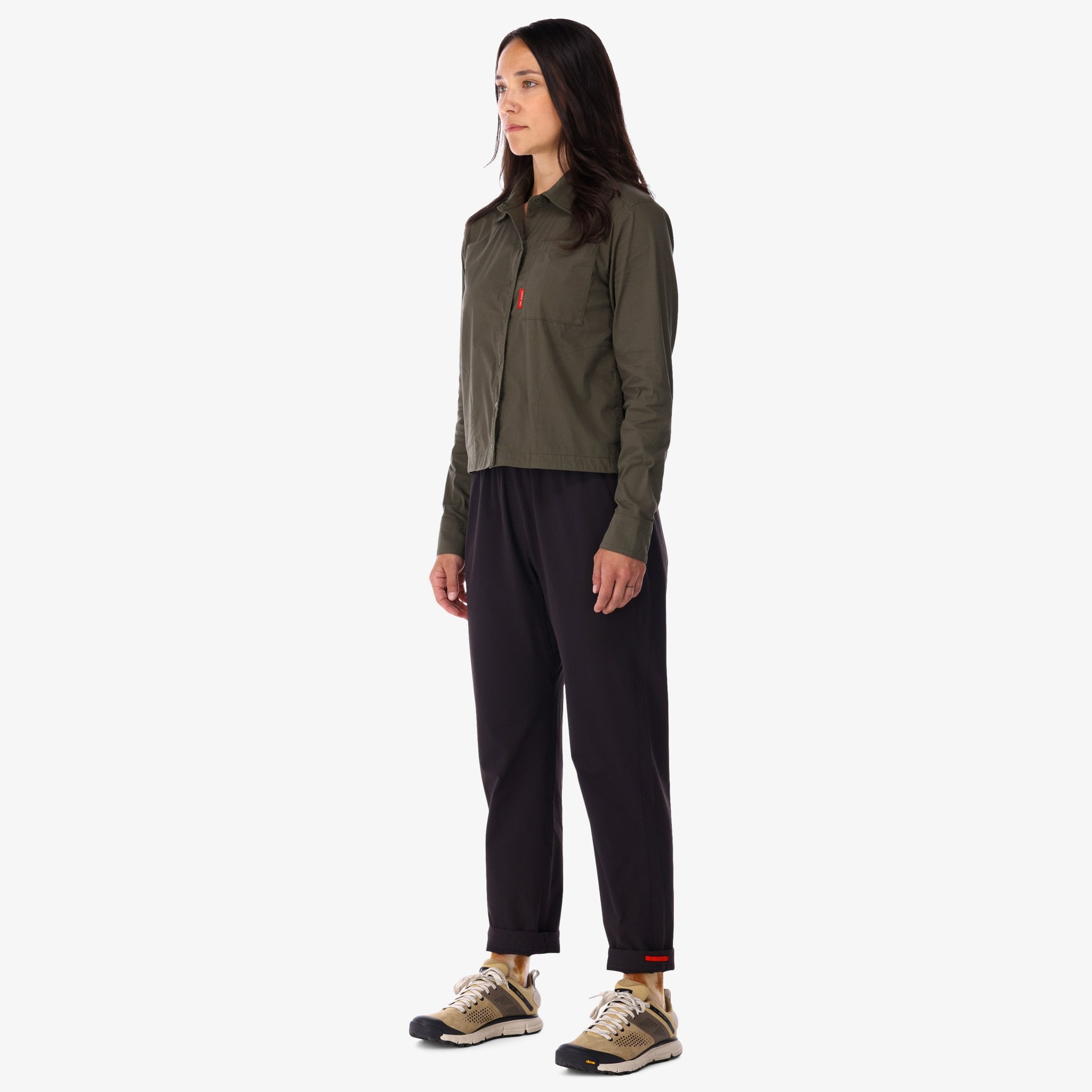 Modèle de côté de la Chemise voyage Topo Designs Femmes Global Manches Longues en vert olive sur le devant du modèle.