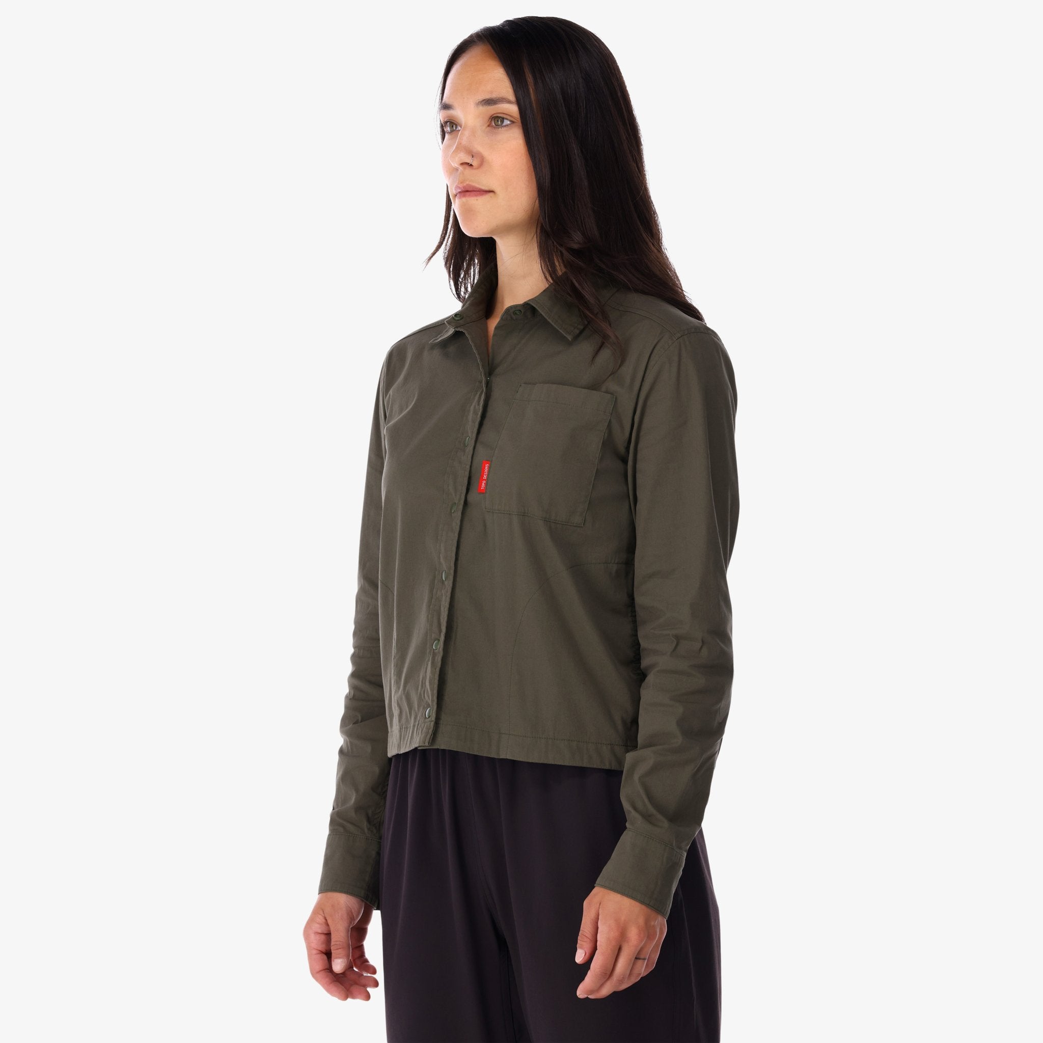 Modèle de côté de la Chemise voyage Topo Designs Femmes Global Manches Longues en vert olive sur le devant du modèle.