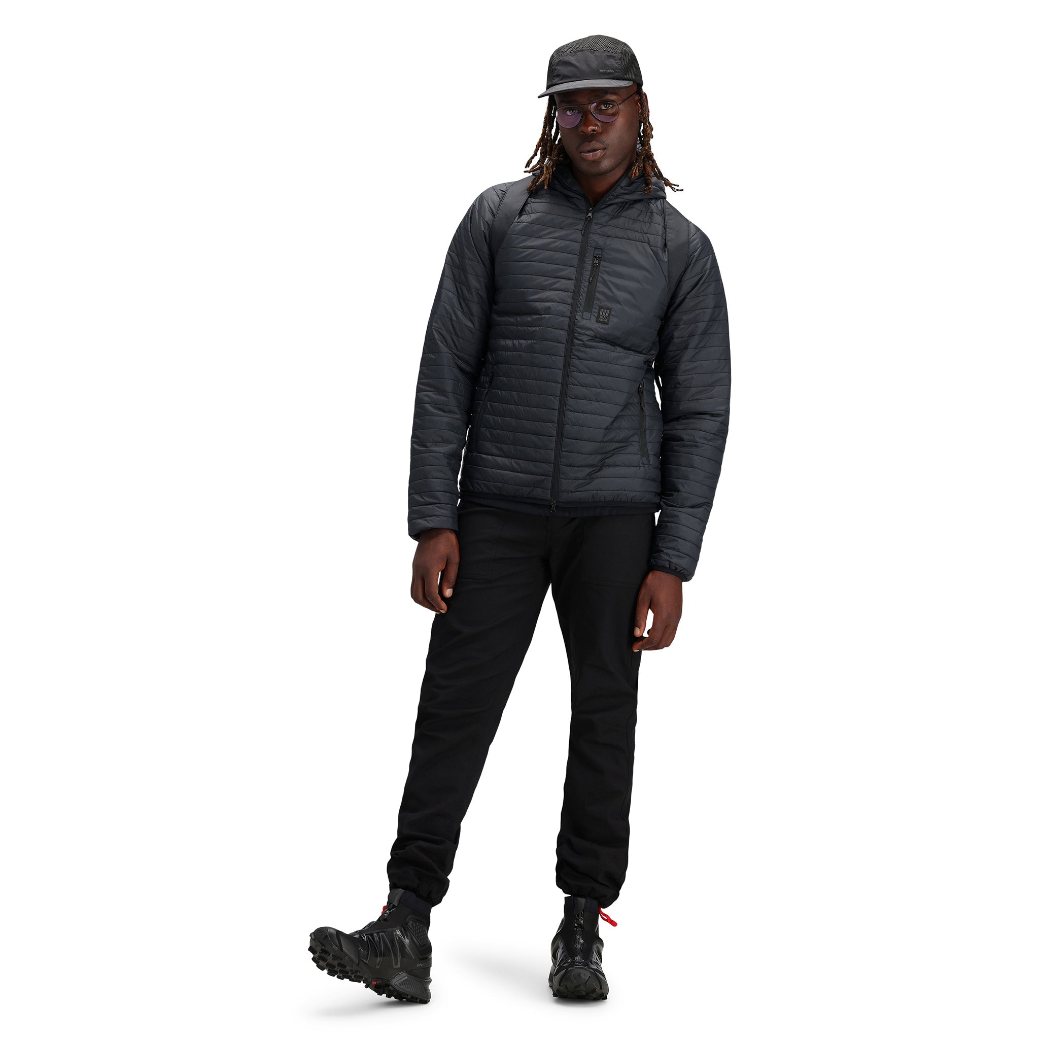 Modèle portant le chapeau Topo Designs Global mesh back en "noir". Chapeau non structuré à 5 panneaux et à bord flexible.