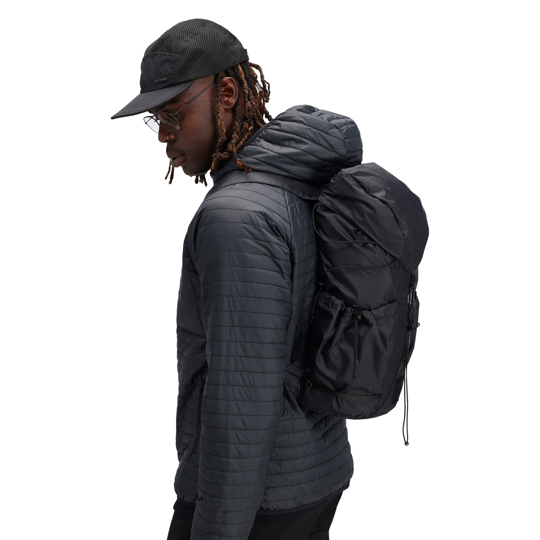 Modèle portant le Topo Designs Hommes Global Puffer packable recycled insulated Hoodie Veste en "black"