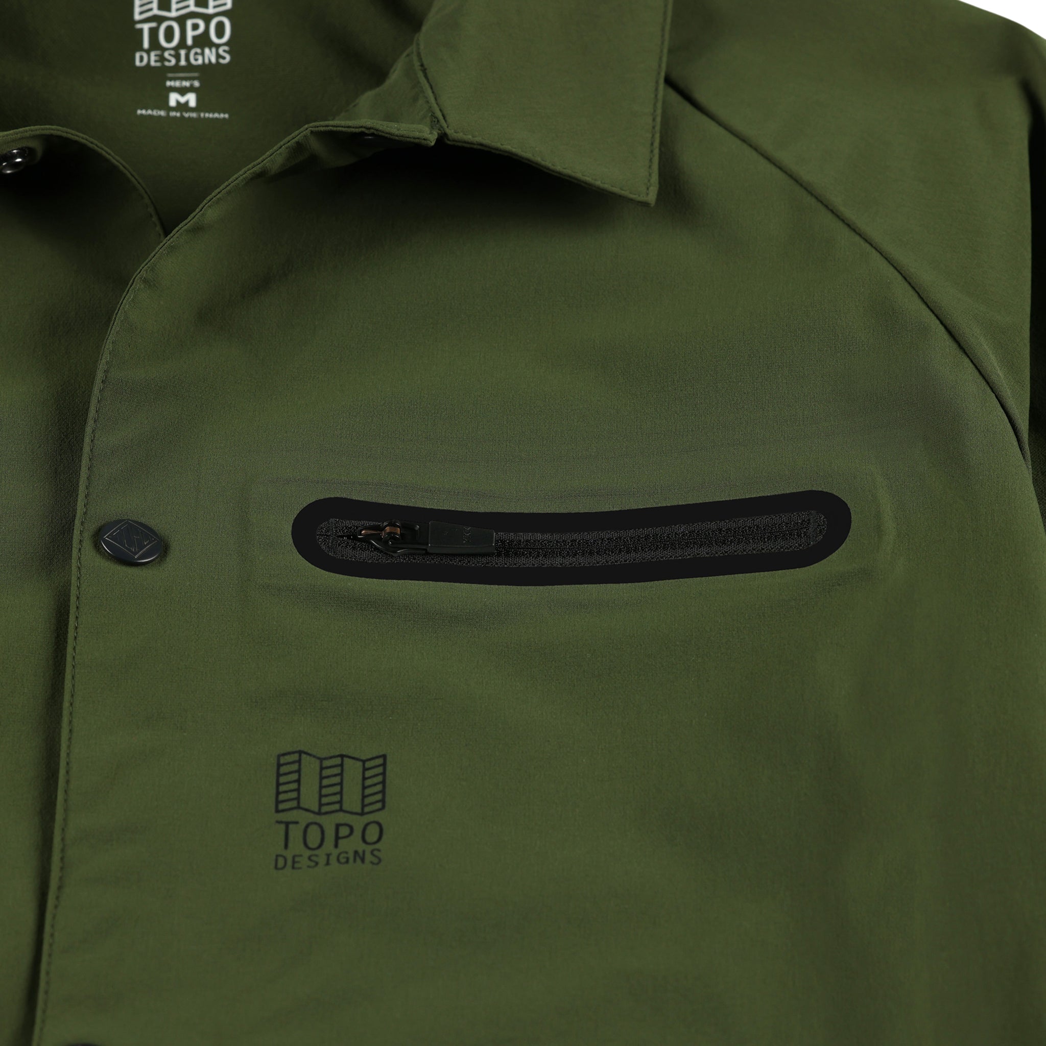 Vue générale de la poche zippée sur la poitrine du coupe-vent Topo Designs Hommes Tech Breaker Veste 4-way stretch en vert olive.