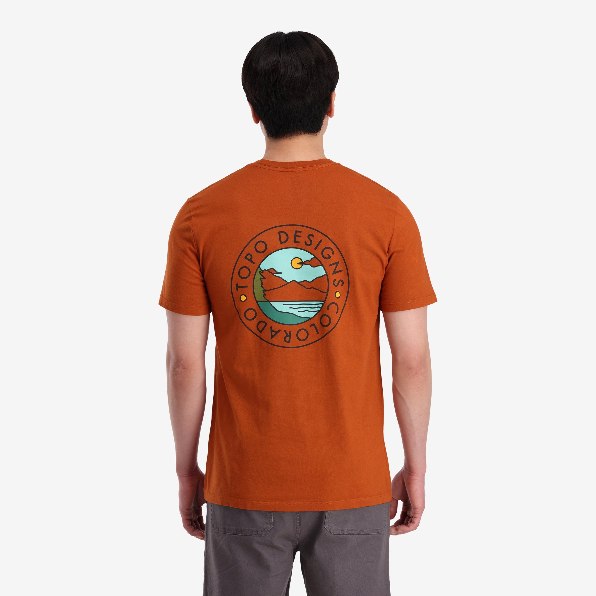 Vue générale du dos du modèle Topo Designs Hommes Camp Logo Tee-Shirt 100% organic cotton graphic Manches Courtes Chemise in "clay" orange.